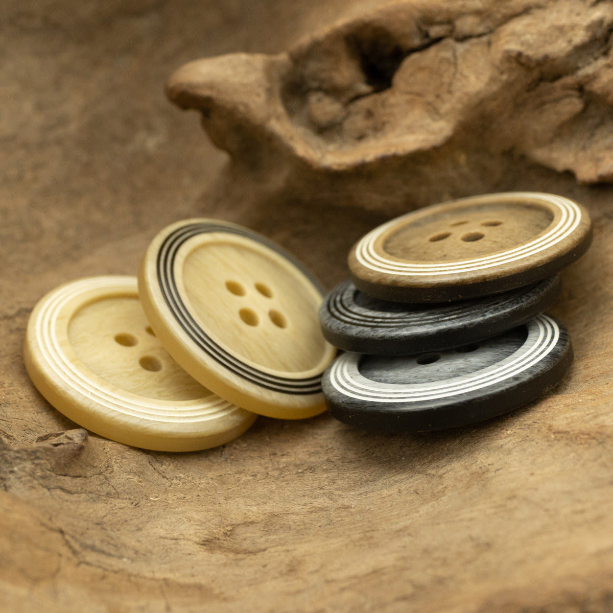 Mixed circular 4-hole buttons with striped rims in light tan, yellow, and dark gray