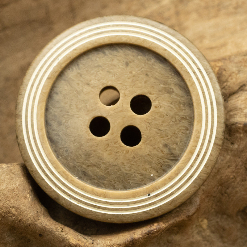 Khaki yellow circular 4-hole button with wood-grain texture and triple-ring striped edge