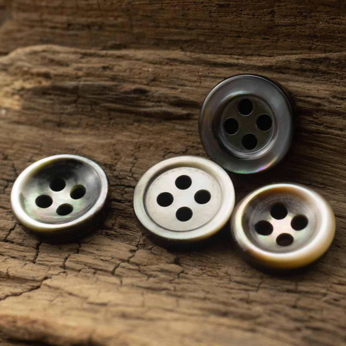 Set of four 4-hole round buttons in dark gray and pearlescent tones.