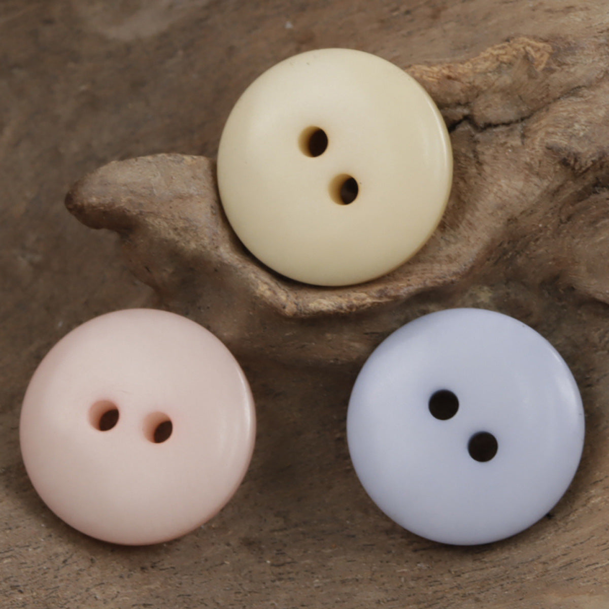Round corozo-style 2-hole buttons in pale pink, cream, and light blue
