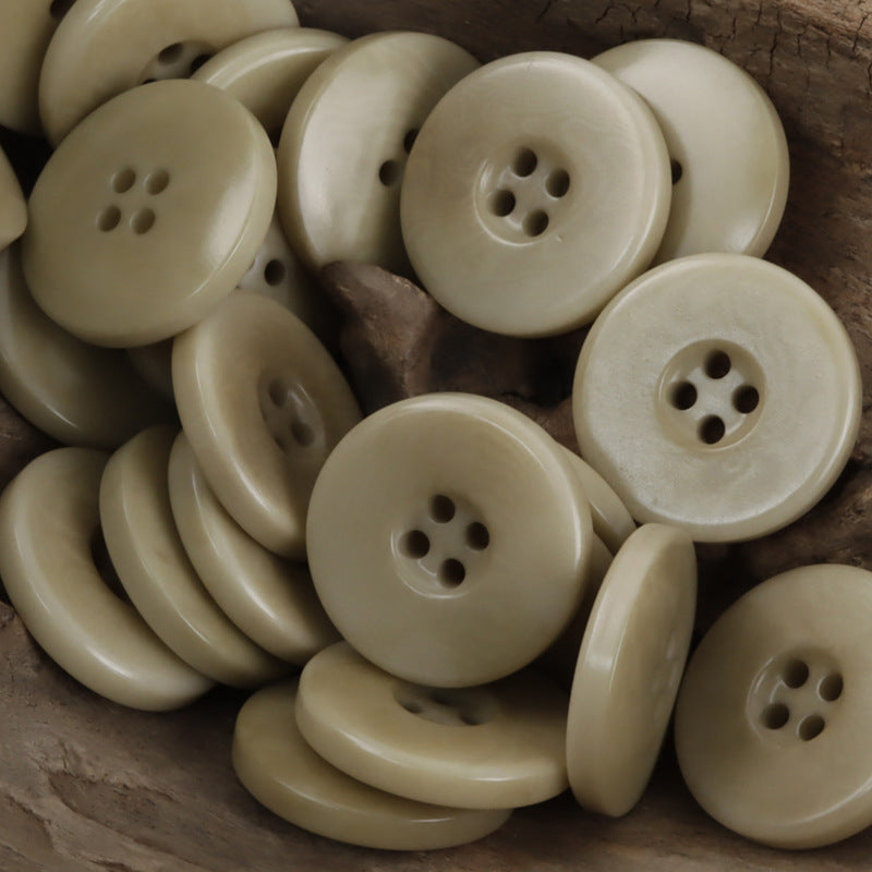 Khaki wide border palm nut buttons, round four-hole fronts, close-up