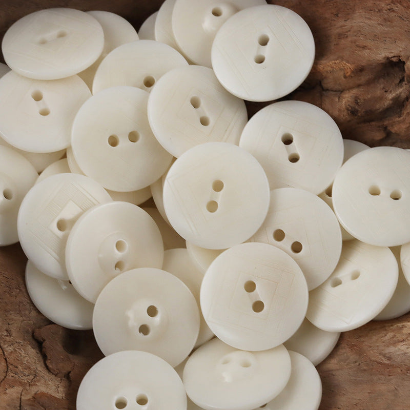 White tagua nut buttons with subtle engraved chessboard pattern and two holes