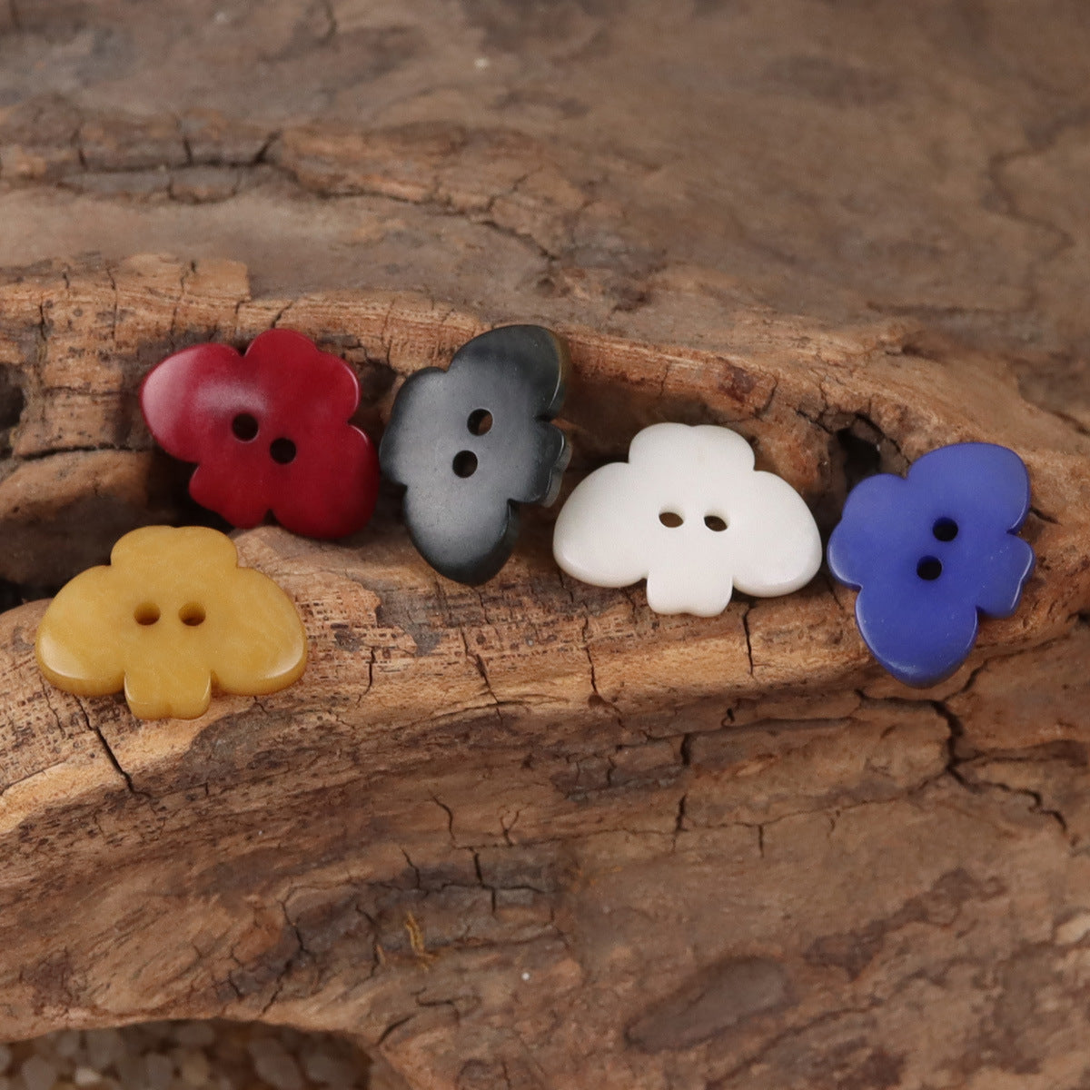 Butterfly-shaped nut buttons in red, dark gray, white, and blue on a flat surface