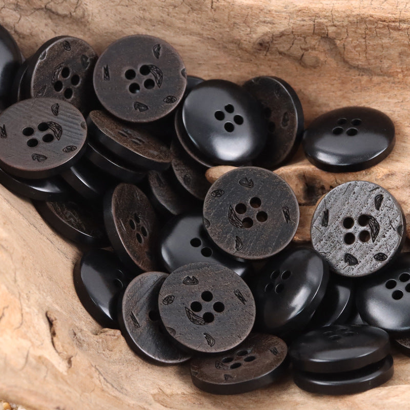 Dark charcoal/black round 4-hole nut buttons with subtle leaf etching