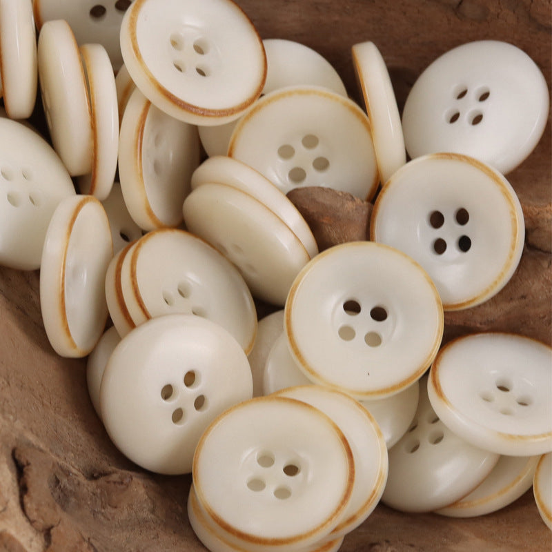 Multiple beige nut-style coat buttons with 4 holes, curved bowl shape