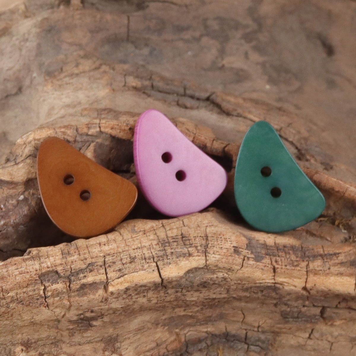 Crescent moon corozo buttons with two holes in brown, pink, and green