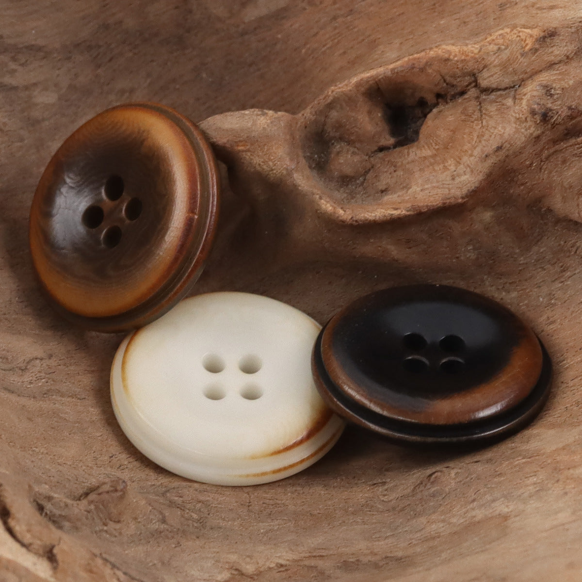 Round coat buttons in brown, white, and dark tones with four holes
