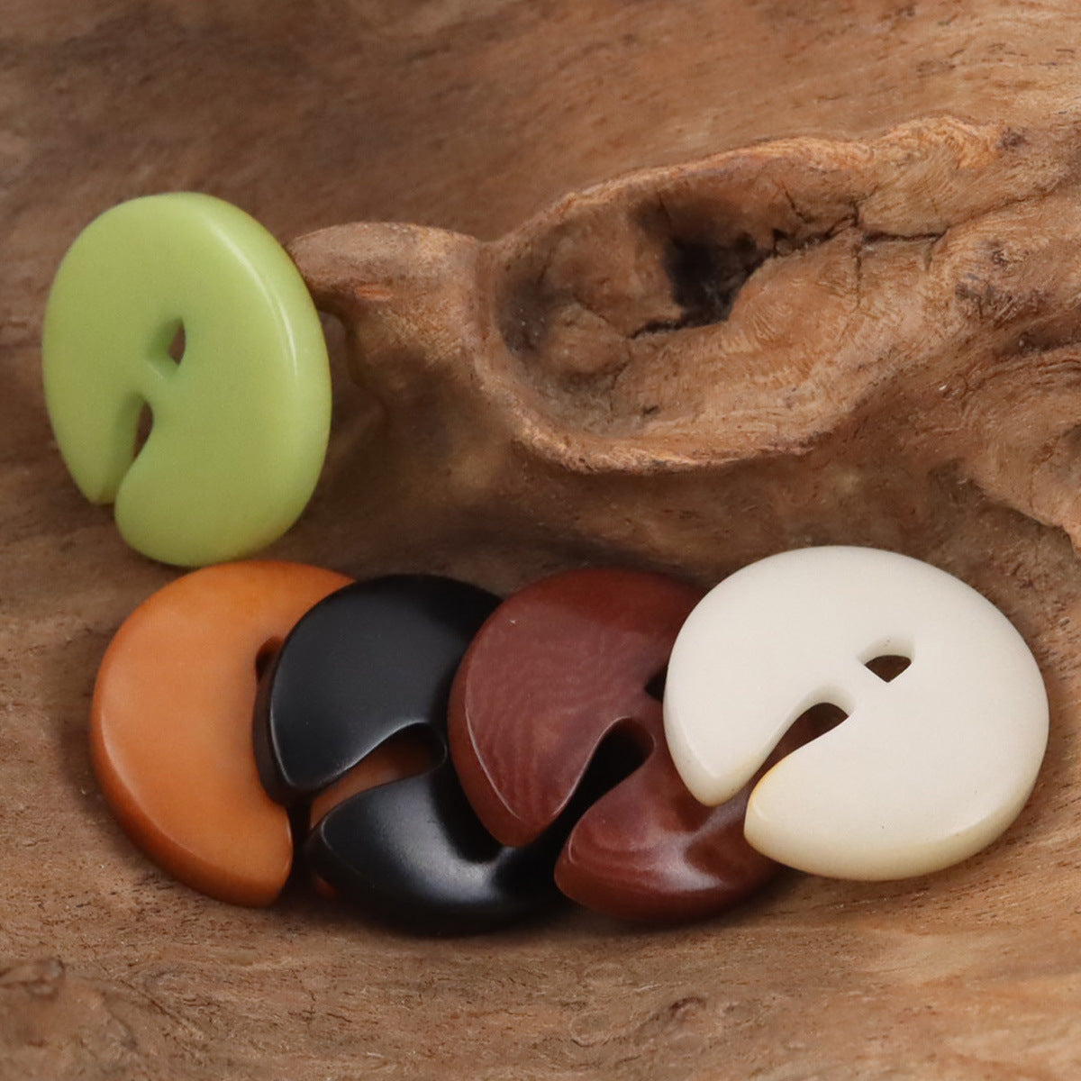 Pac-Man tagua nut buttons in light green, orange, dark maroon, black, and cream