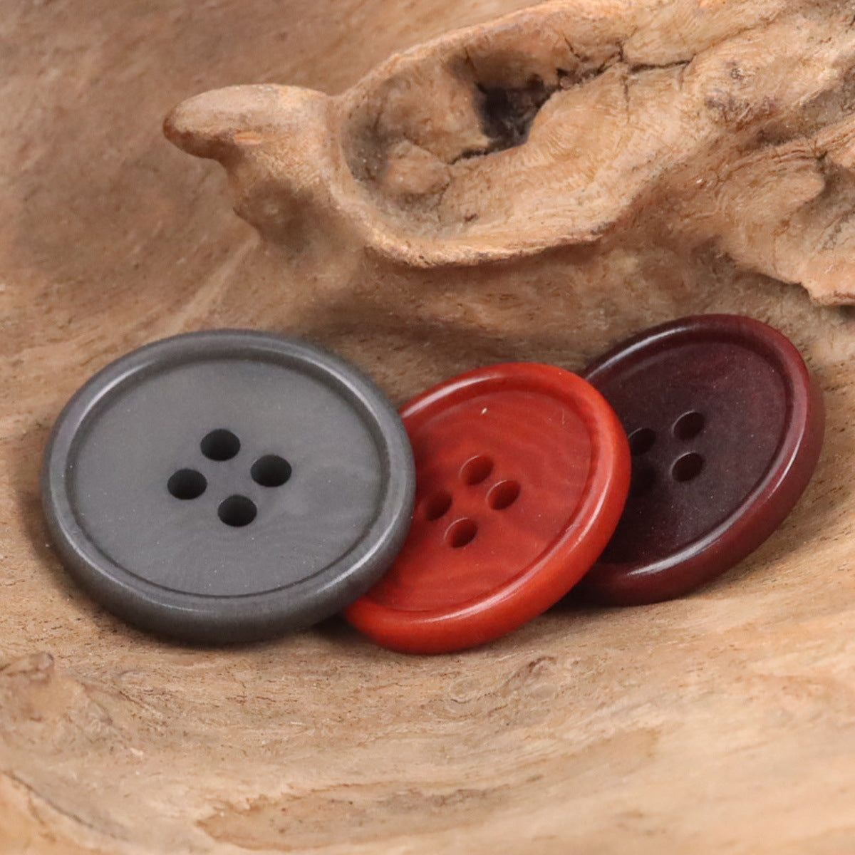 Round buttons in deep gray, dark red, and red, each with four holes