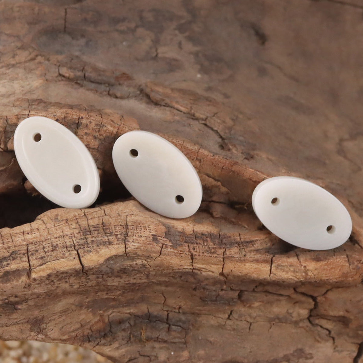 Set of beige long oval two-hole tagua nut buttons on wooden surface