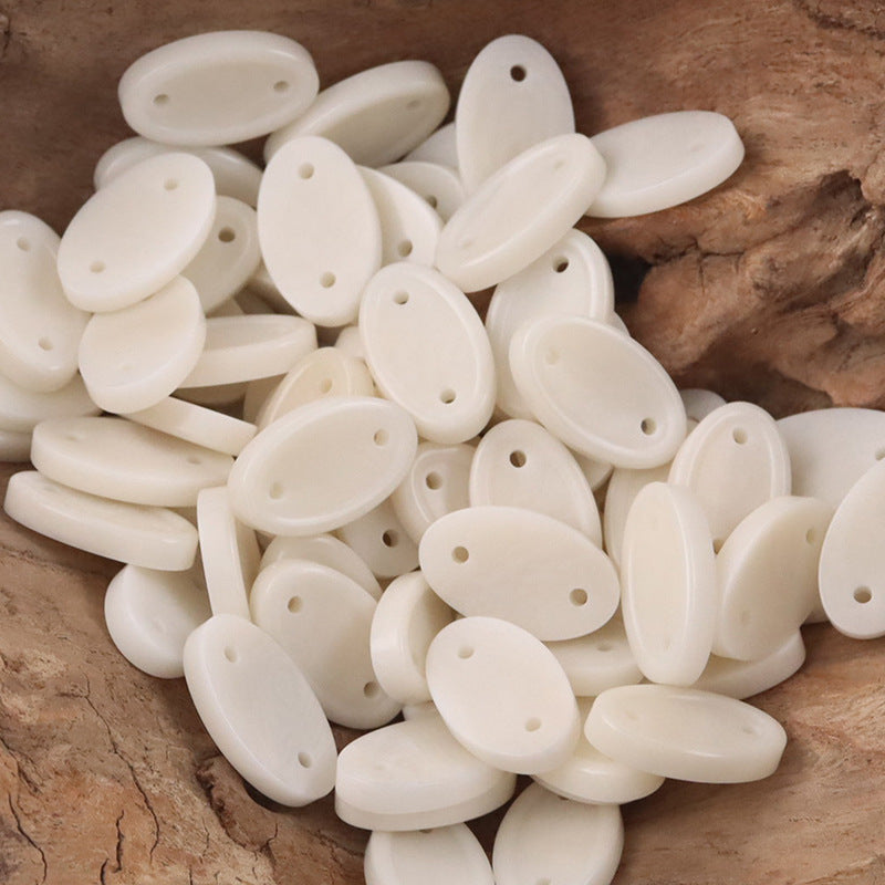 Assorted beige long oval two-hole tagua nut buttons, bulk pile