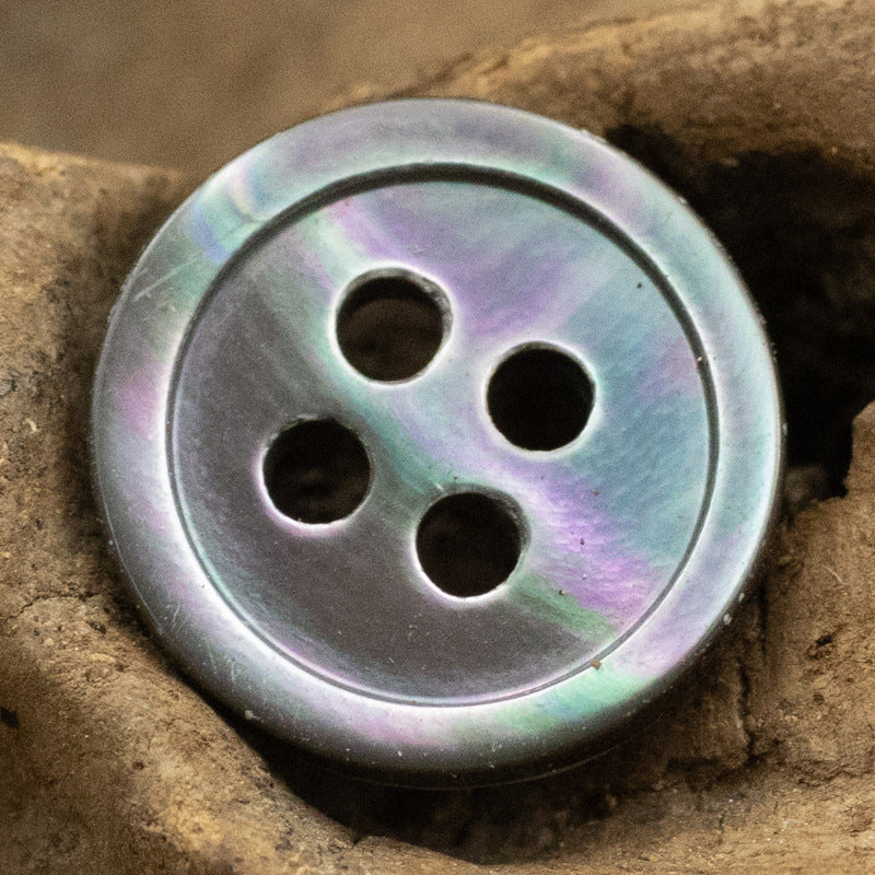 Round 11.5mm shell button, 4-hole—iridescent silver/gray with rainbow sheen (close-up).