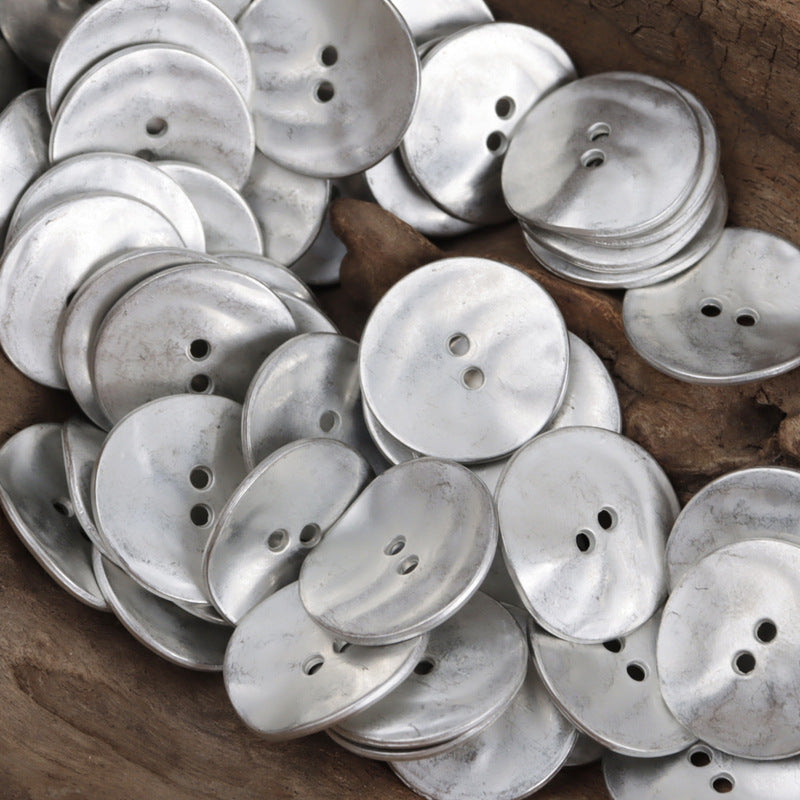 Pile of matte silver curved metal buttons, round with 2–3 holes; 10-pack