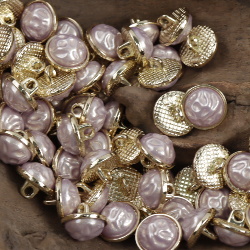 Close-up of Chinese-style buttons: light pink domes with embossed swirl pattern on metal bases
