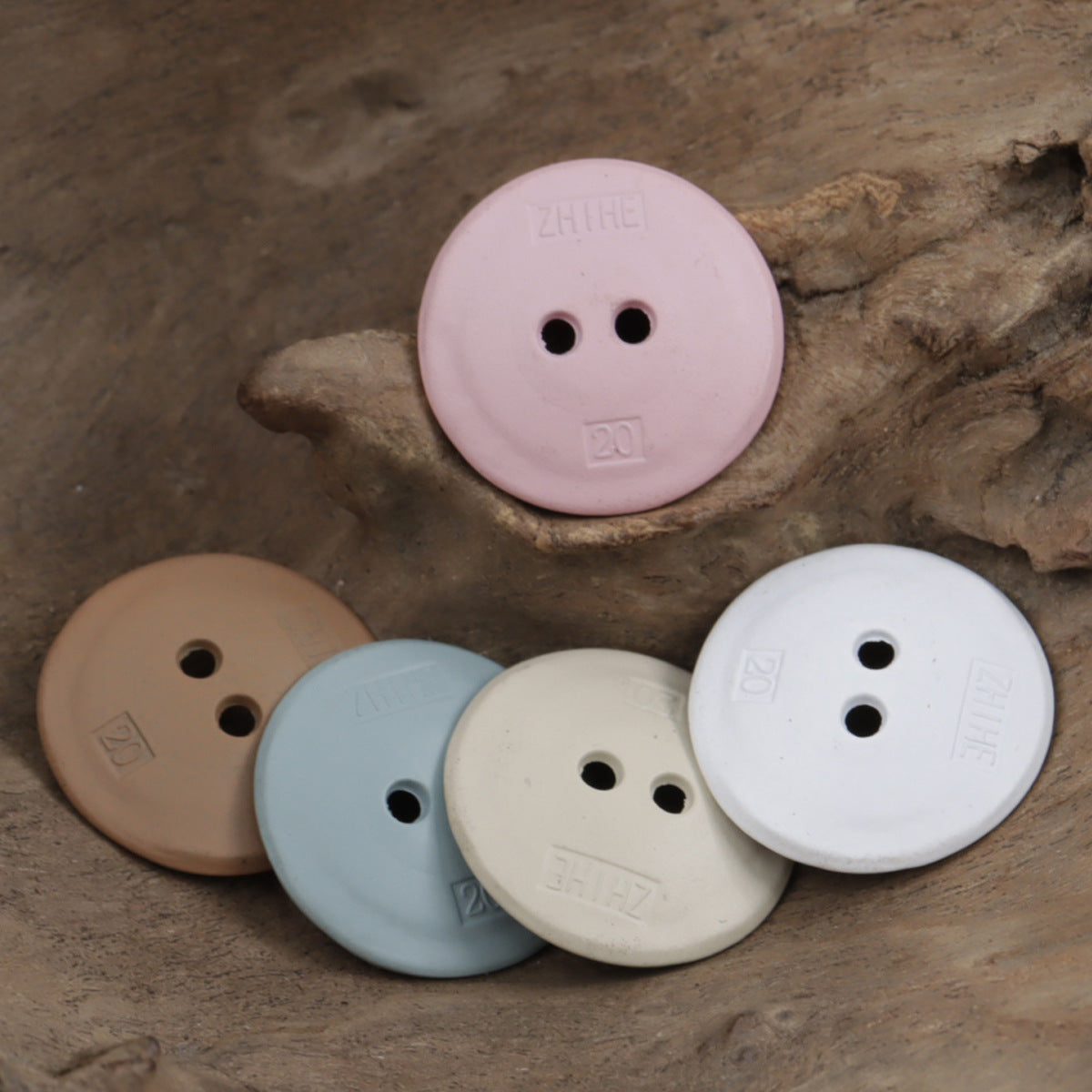 Round two-hole buttons in pink, light blue, white and beige, stacked together