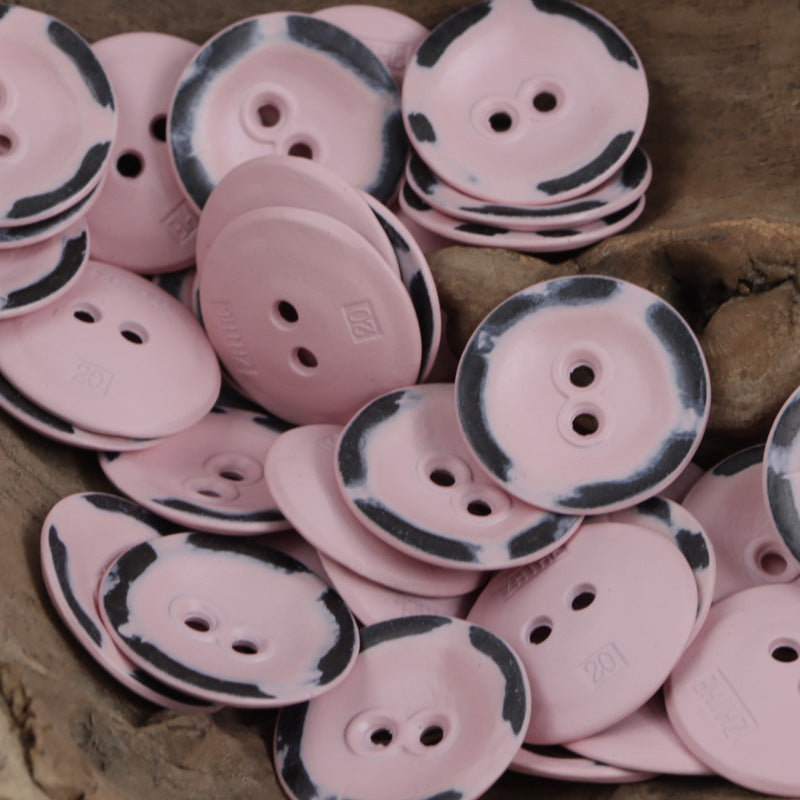 Two-hole metal buttons in pink shades, some with dark speckle rim, stacked
