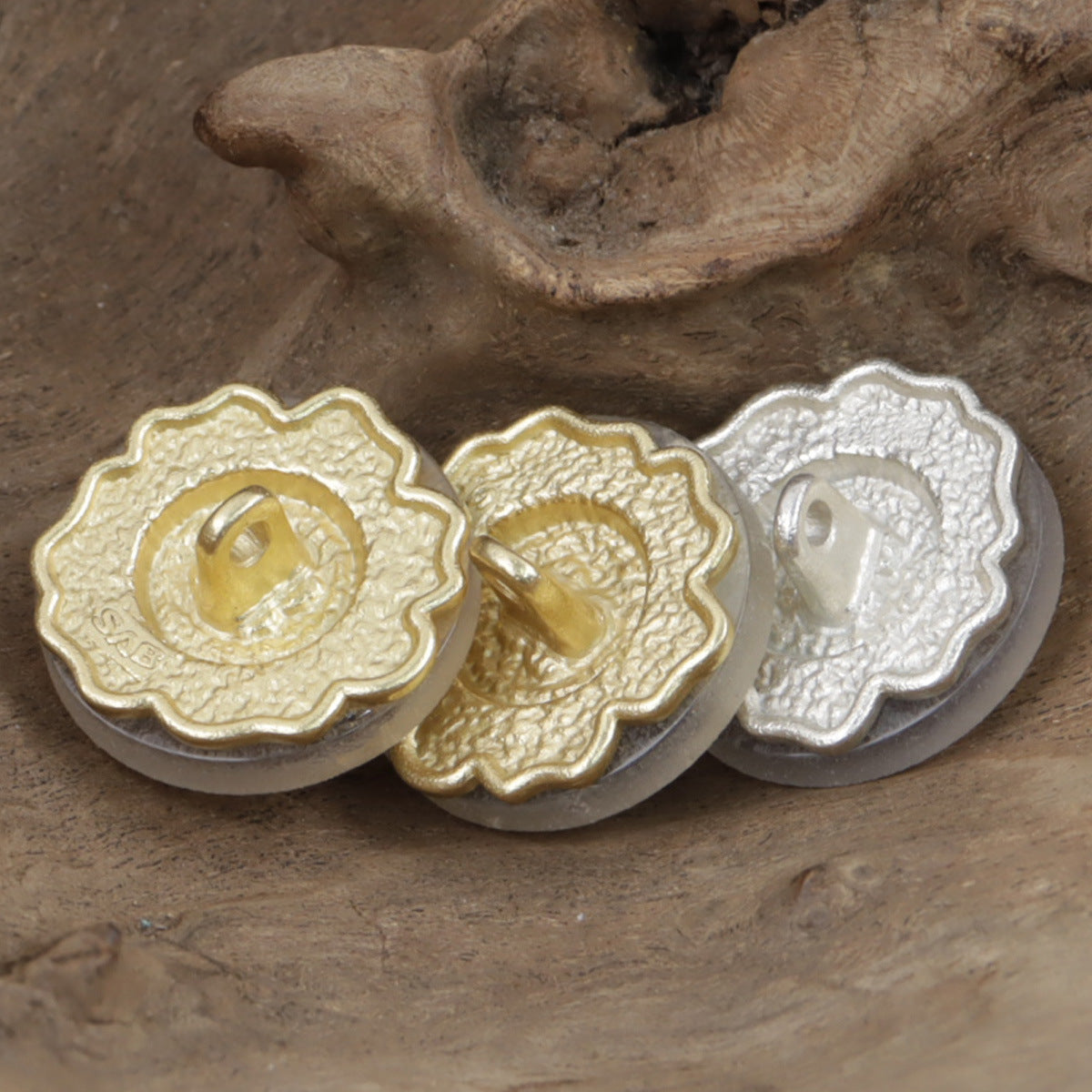 Gold and silver small flower metal buttons, backside with pinholes visible