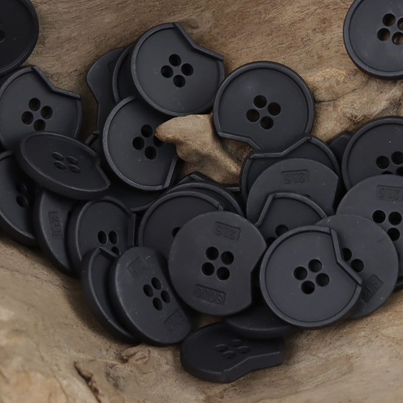 Irregular notched 4-hole metal buttons, close-up in matte dark black finish
