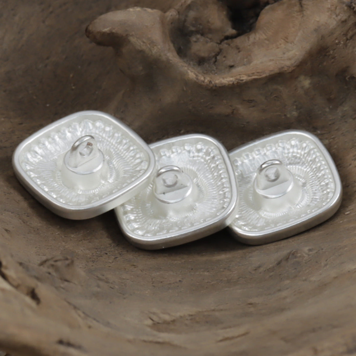 Silver square metal shank buttons with rose center and pearl edging, angled view