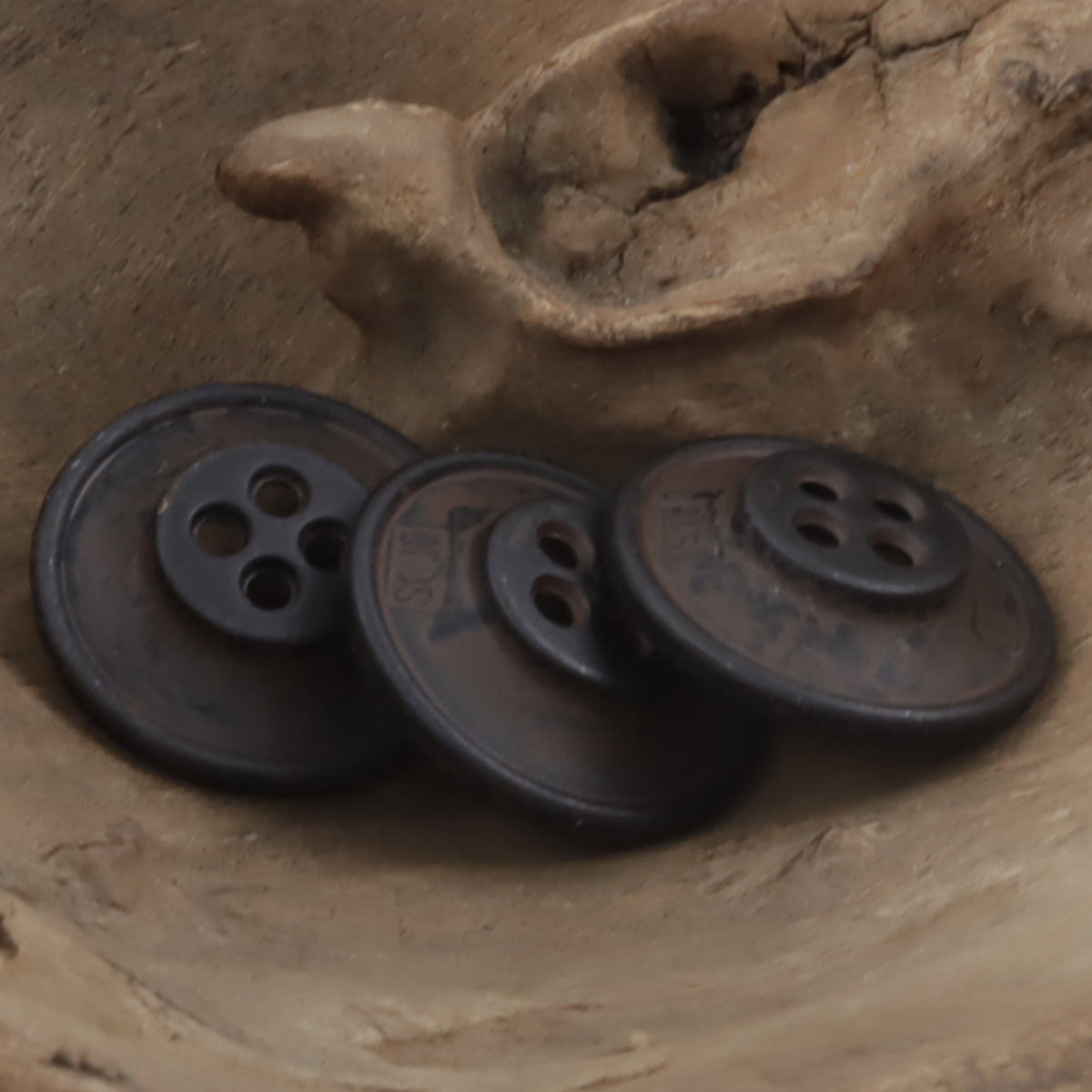 Vintage denim buttons with dark patina, side view and four-hole face