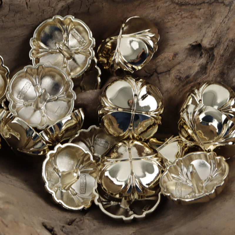 Four-leaf clover metal shank buttons, silver and misty/light gold tones in a pile