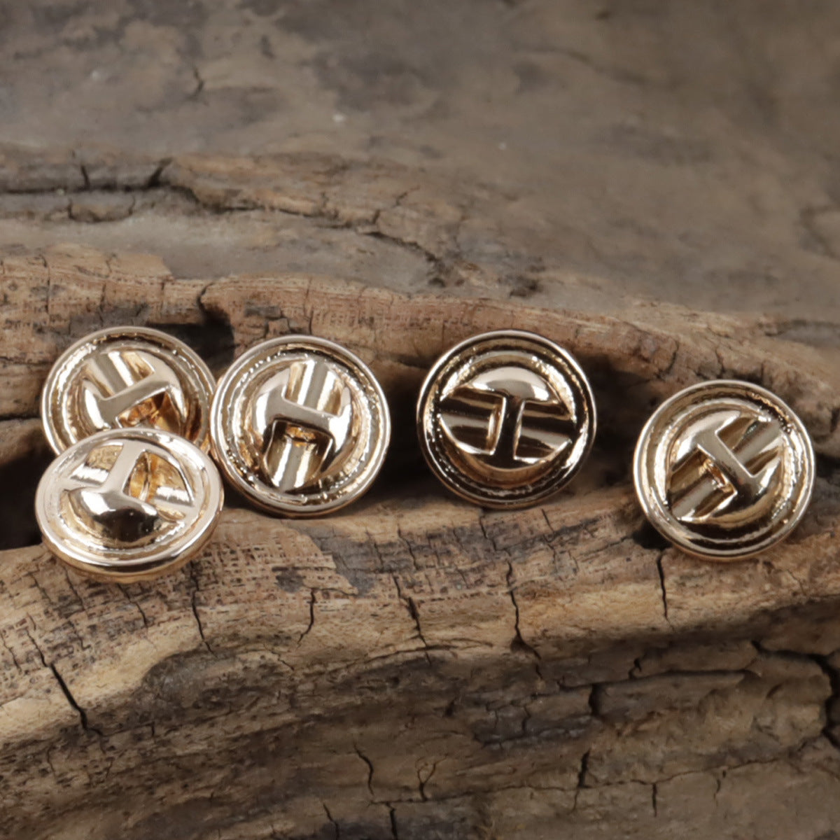Round metallic shirt buttons with cross-like engraving, silver-tone backs and posts