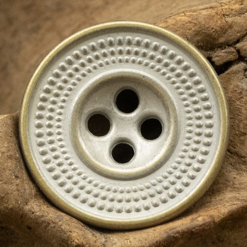 Antique cap-shaped metal button in light tin/bronze with embossed dot border