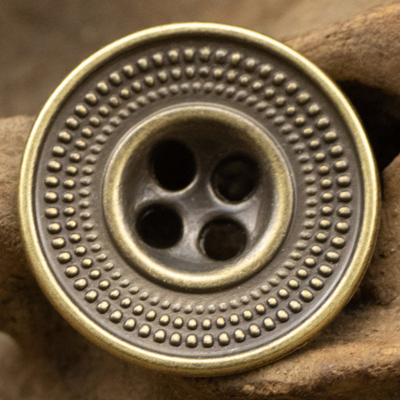 Antique cap-shaped metal button in bronze tone with embossed dotted rim and 4 holes