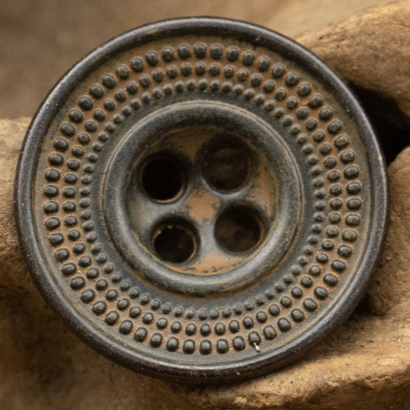 Antique cap-shaped metal button in dark rusty tin with embossed dot ring and 4 holes