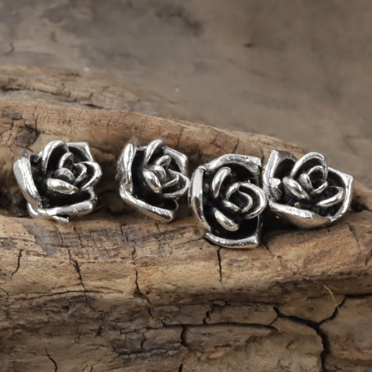 Set of mini silver rose shank buttons, 10mm, four visible on wood planks