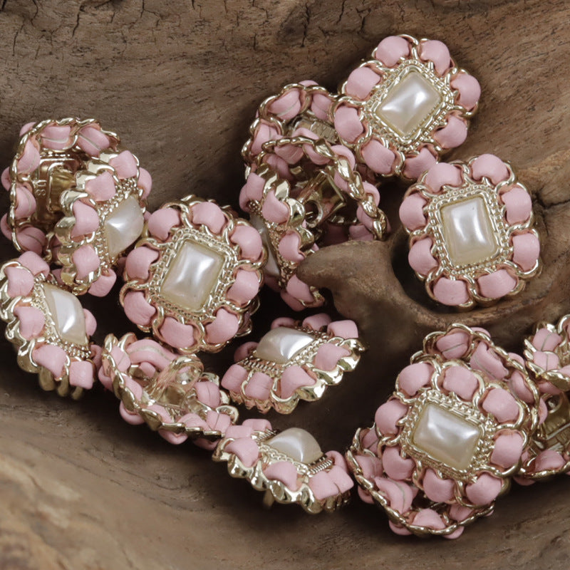 Pink square metal pearl buttons with leather cord weaving, clustered close-up