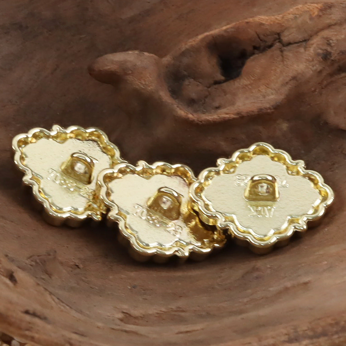 Back view of golden metal buttons, irregular shape with raised shank openings