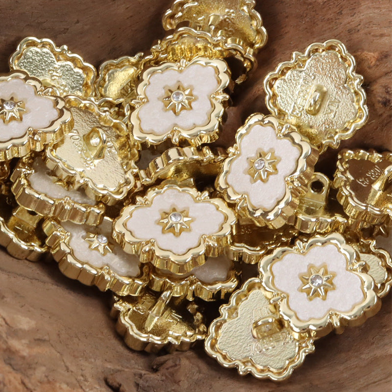 Irregular metal buttons with gold edging, white inlay, and small star gem detail