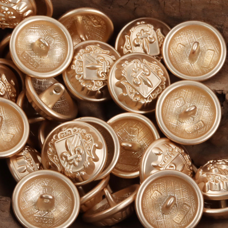 Rose gold metal shank buttons with shield-sword crest detail, multiple pieces