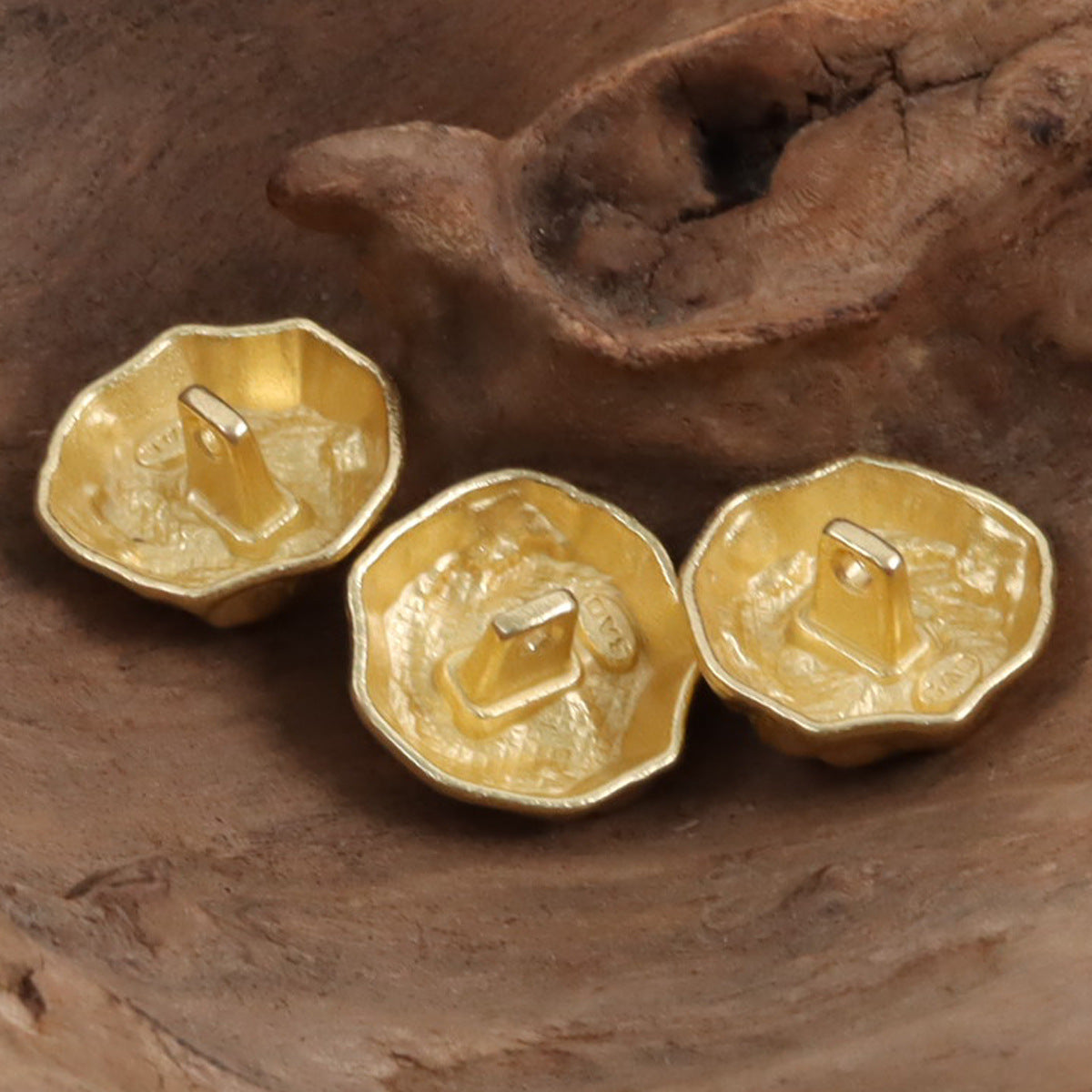 Gold rock-shaped metal buttons showing embossed front relief and back loop shanks