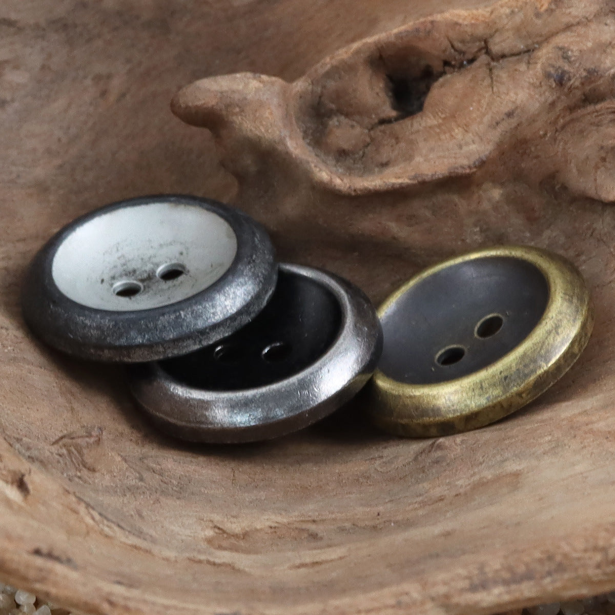 Two-tone metal buttons with distressed engraving, round faces, two holes each