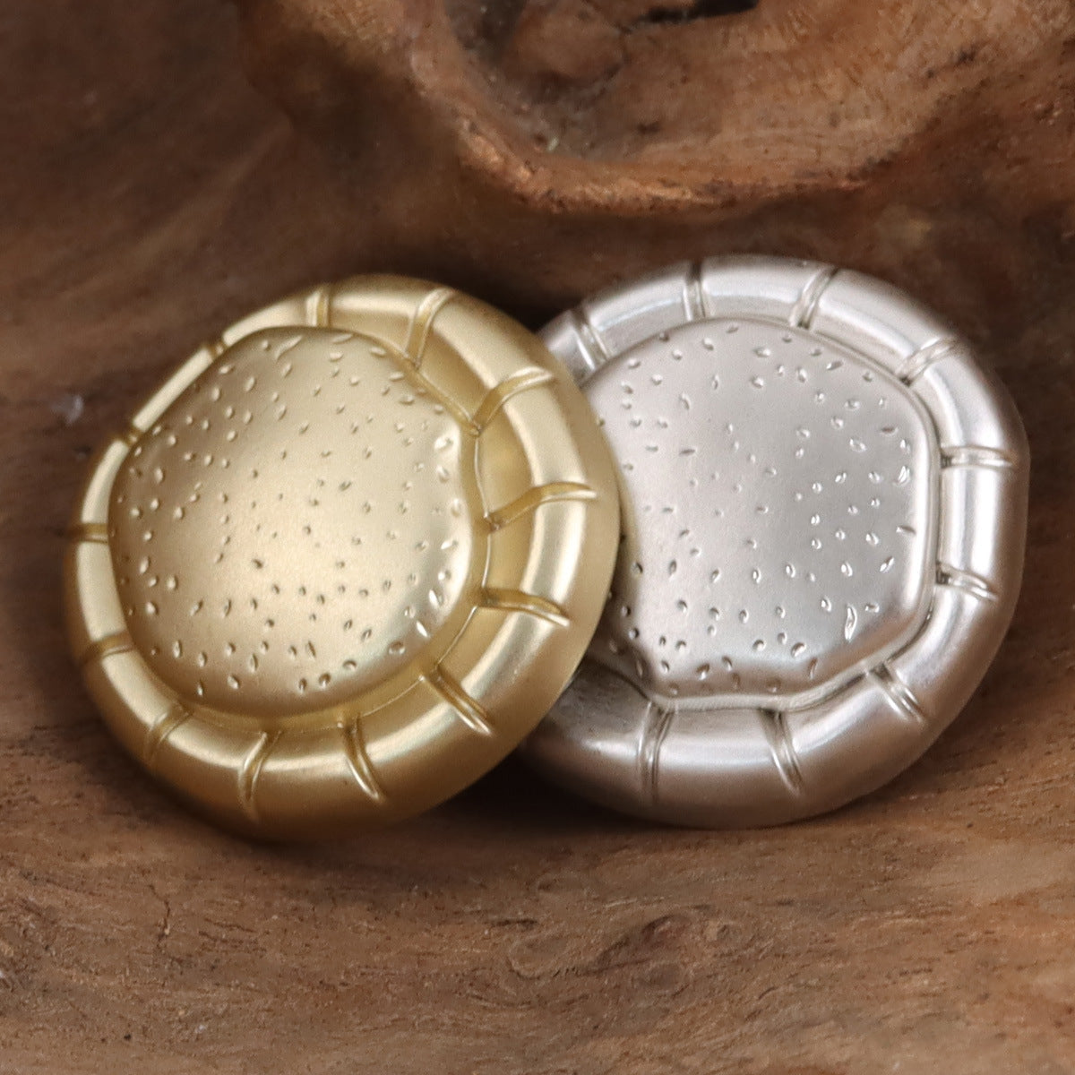 Two matte metal fashion buttons, gold and silver, studded domed front panels
