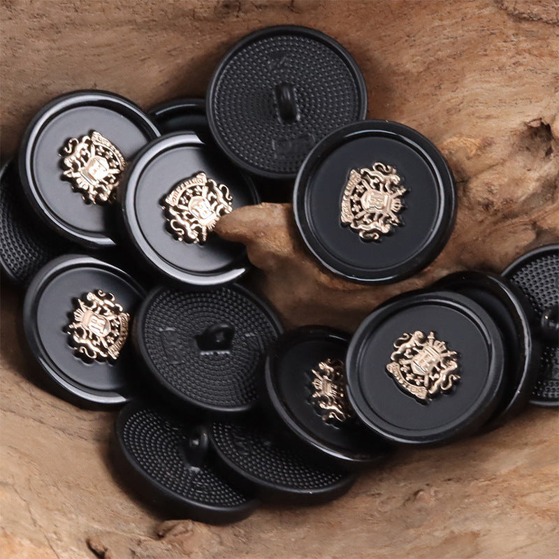 Assorted black shank buttons with gold crest emblems and textured faces, multiple