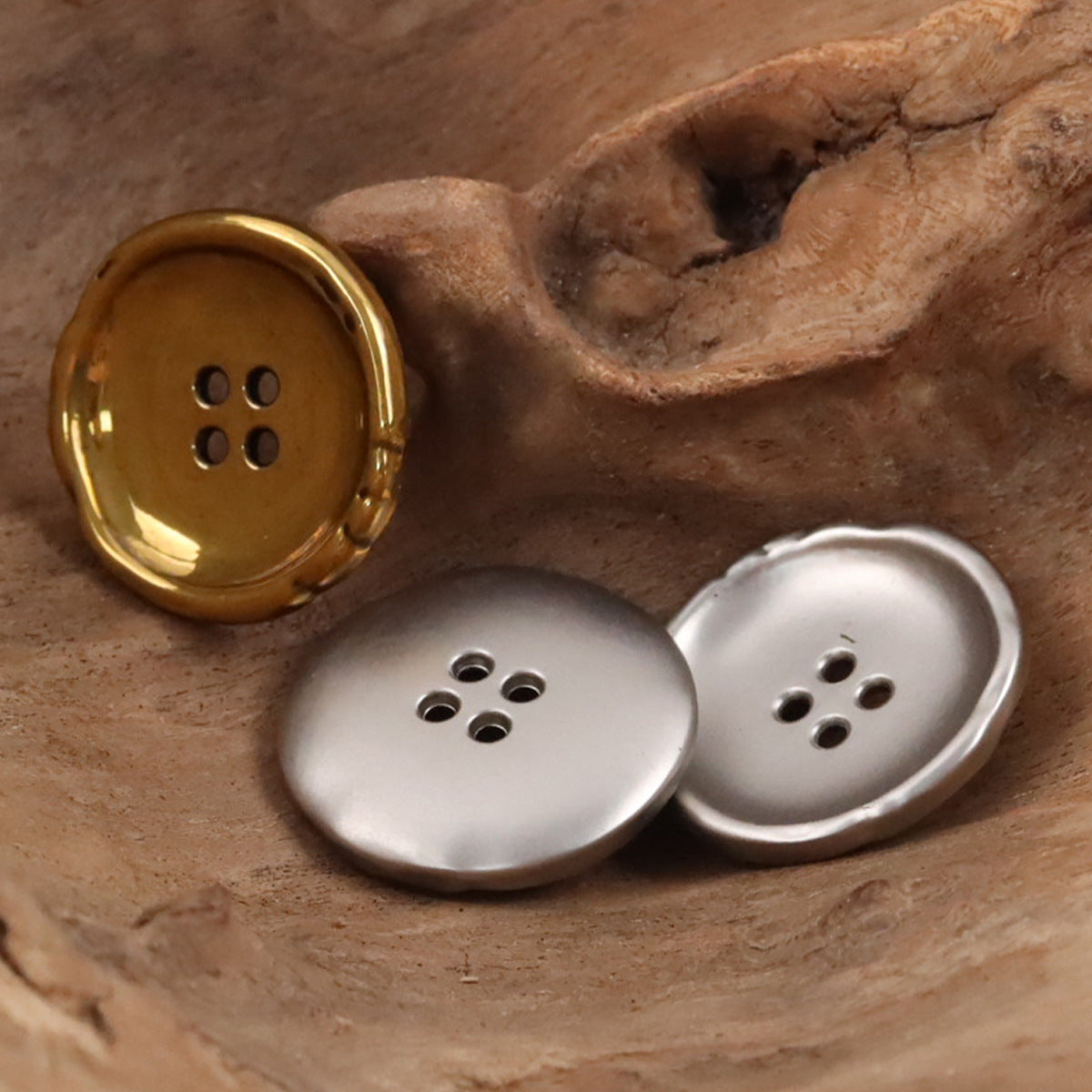 Irregular metal buttons: one gold and two silver, round 4-hole design.