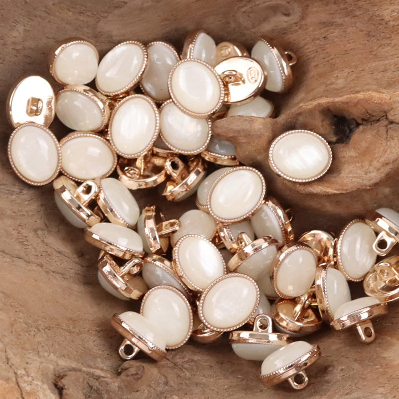 Oval resin pebble shank buttons, white fronts with rose-gold rims.