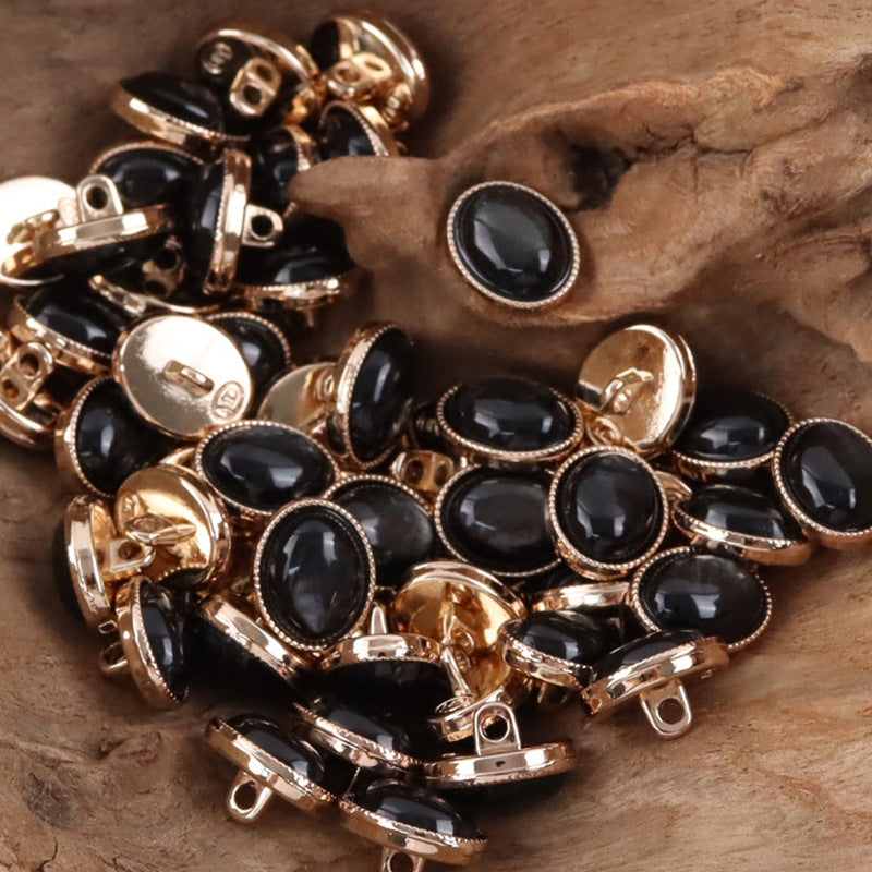 Oval resin pebble shank buttons, dark fronts with gold-toned rims.
