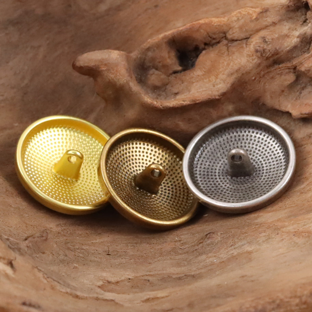 Set of metal shield buttons showing underside backs in gold, bronze, and silver tones