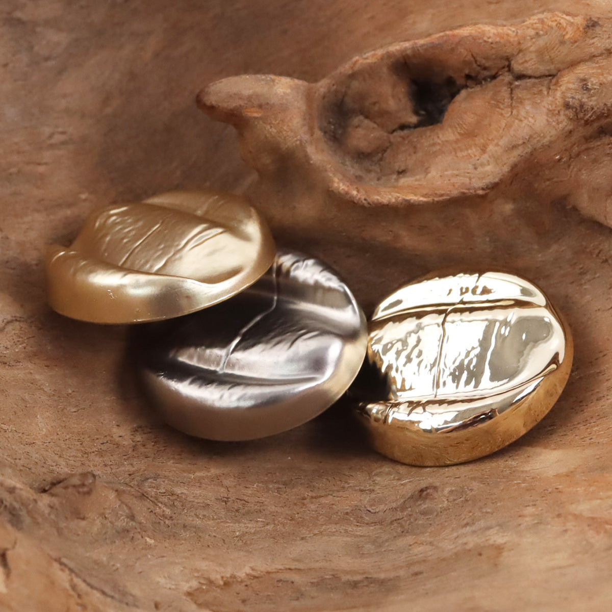 Gold and rose-gold irregular oval metal shank buttons, front details