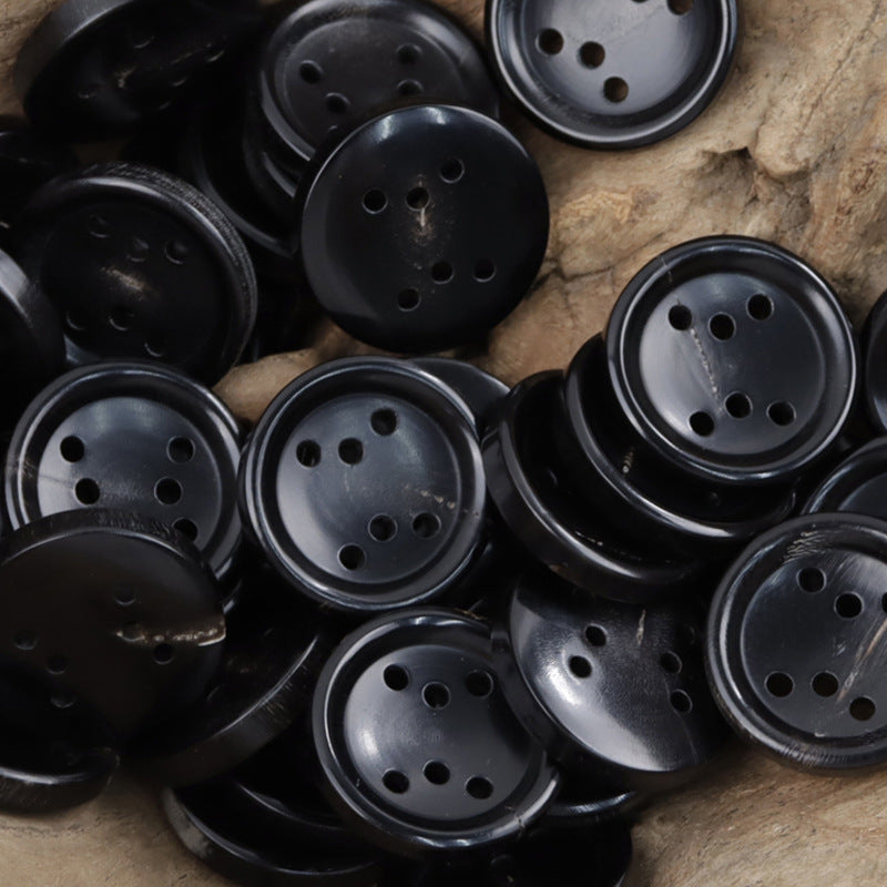 Set of black six-hole round buttons on tan leather, multiple pieces for jackets