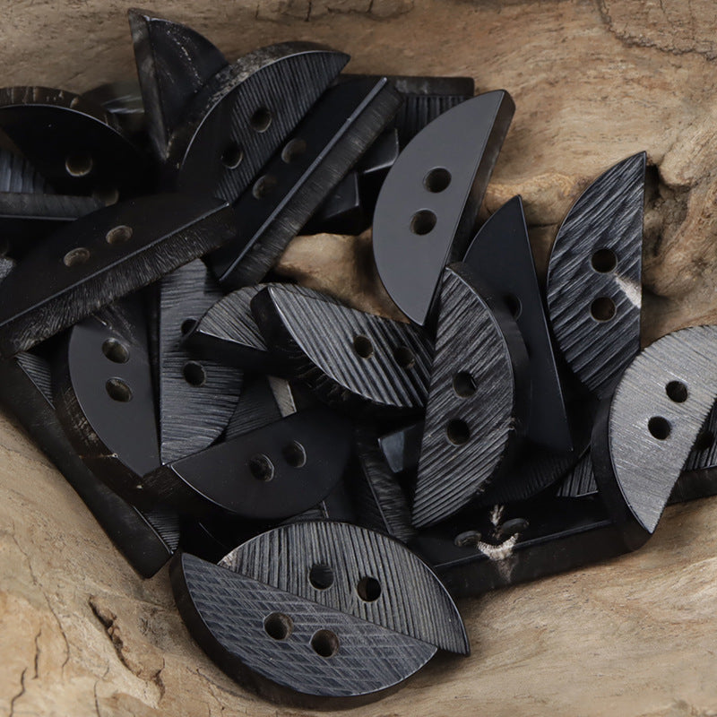 Assorted crescent-shaped dark decorative buttons with textured finish and two holes