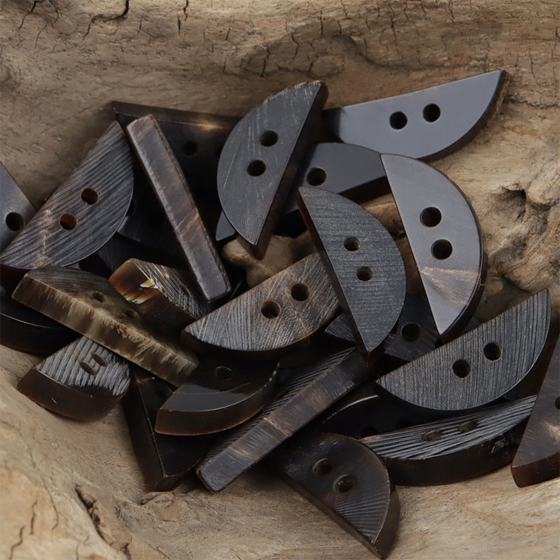 Mixed dark crescent slant-cut decorative buttons with textured grain and single holes