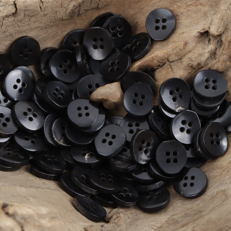 Black 4-hole horn buttons, pear-shaped, close-up top view