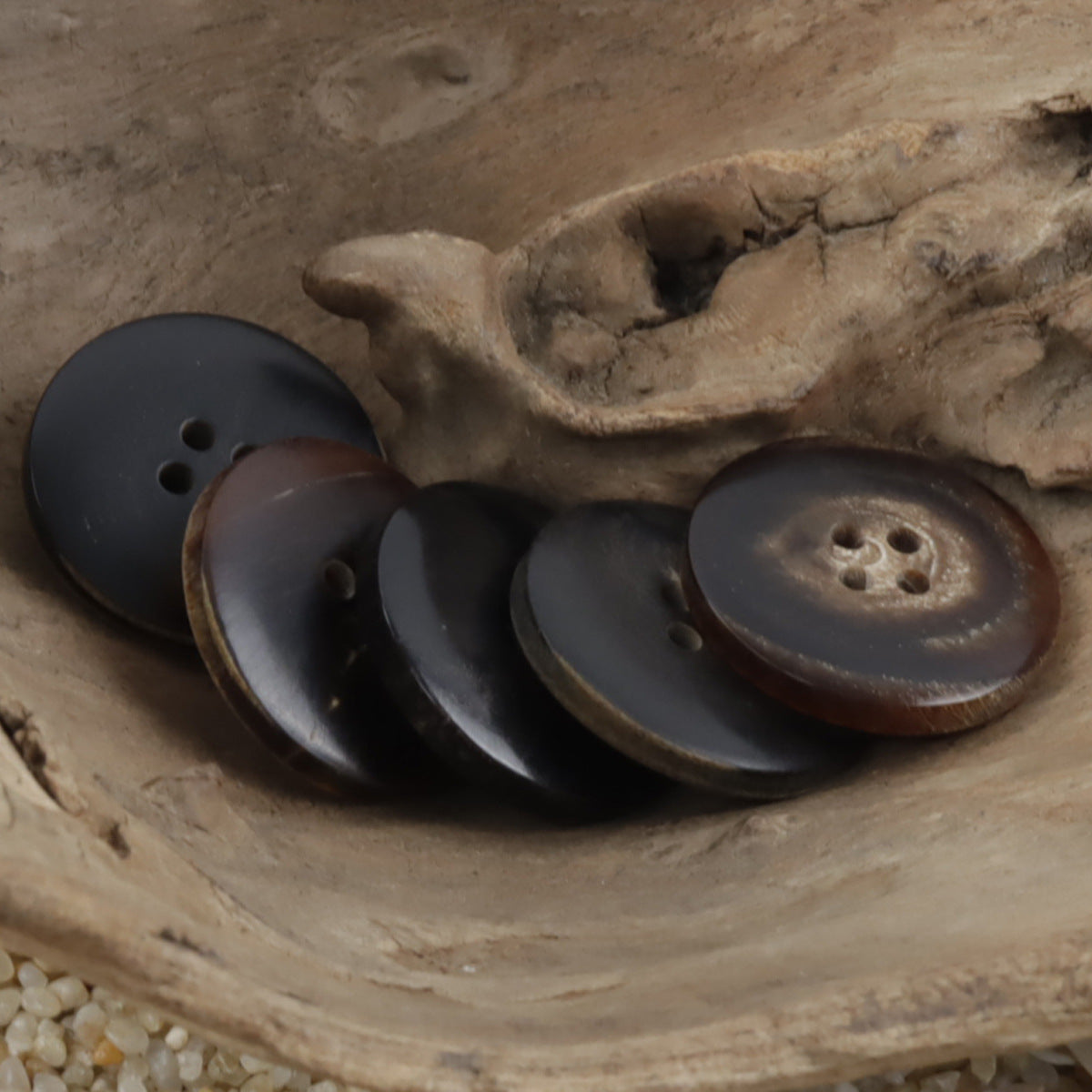 Horn-look buttons in dark finishes, round 4-hole design with engraved border trim