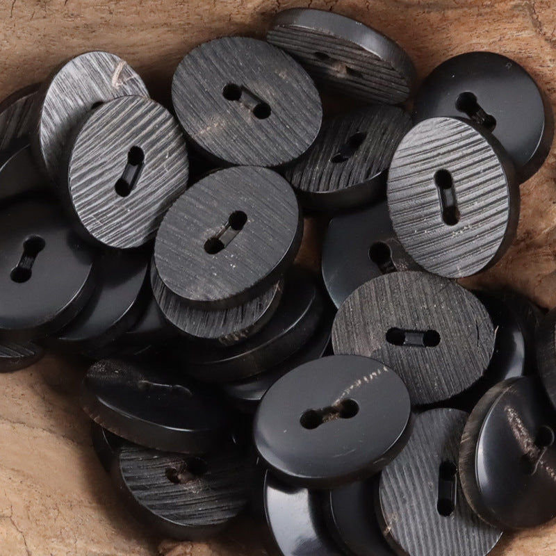 Black horn buttons with textured ridges and split-hole eyelets, round set, close-up