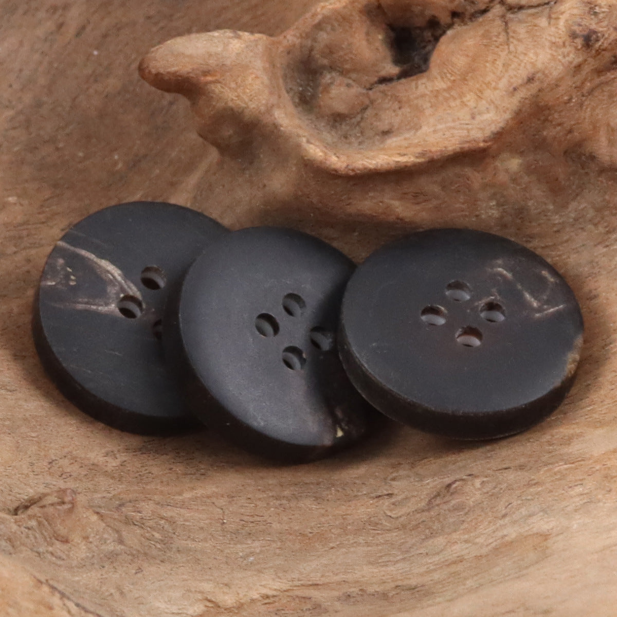 Dark cow horn buttons with oval shape and four-hole front cutouts
